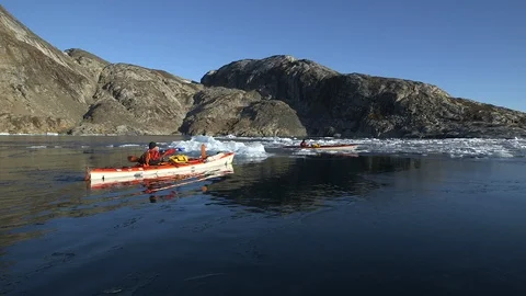 Two kayakers sailing in the middle of the ice floe, Greenland Stock Footage 104185501