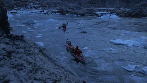 Two kayakers sailing in the middle of the ice floe, Greenland Stock Footage 104189703