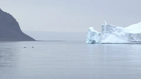 Two kayakers sailing next to a big iceberg in the Arctic Ocean, Greenland Stock Footage 103361963