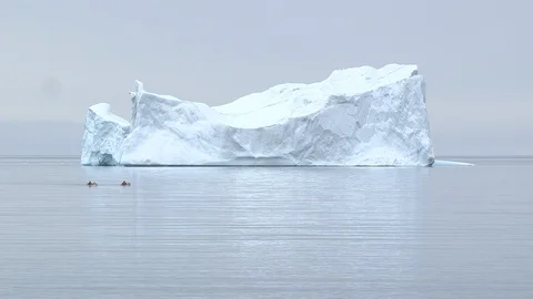 Two kayakers sailing next to a big iceberg in the Arctic Ocean, Greenland Video stock 103363969
