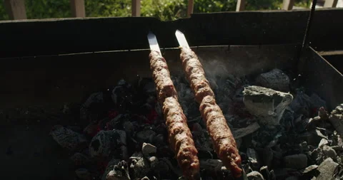Two kebabs cooking over hot charcoal, traditional barbecue technique. Ideal for Stock Footage 266109345