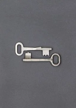 Two keys on gray paper background, close up Stock Photos