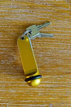 Two keys with a heavy gold hotel fob on wooden surface in soft light Stock Photos