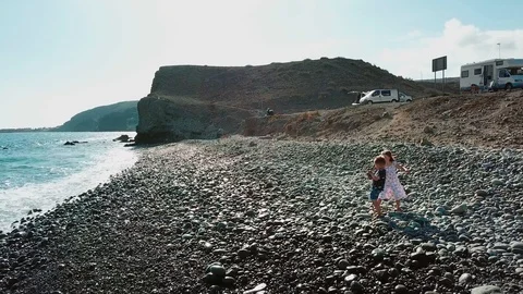 Two kids are playing with ocean waves at the shore. Kids are running from waves Stock Footage 95897071