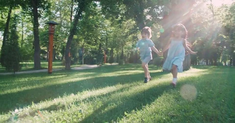 Two kids,a boy and a girl running around in the garden holding hands and Stock Footage