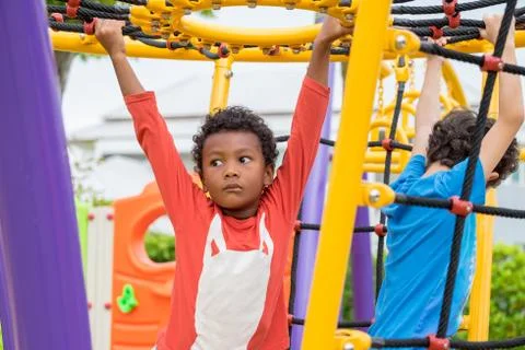 Two kids boy having fun to play on children's climbing toy at school playgrou Foto stock