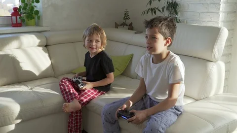Two kids emotionally playing videogames at home at sunny morning Video stock 97739802