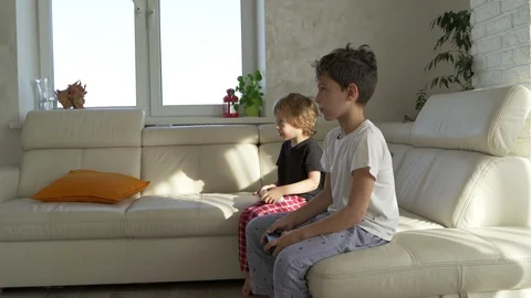 Two kids emotionally playing videogames at home at sunny morning Video stock 97744314