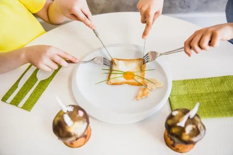 Two kids hands eat easter breakfast with cute bunny made of eggs in bread. Ea Stock Photos