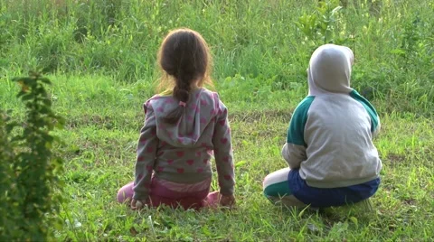 Two kids have fun on green grass play and fight, back to camera Stock Footage 63395761
