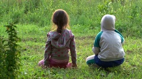 Two kids have fun on green grass play and fight, back to camera Stock Footage 63395802