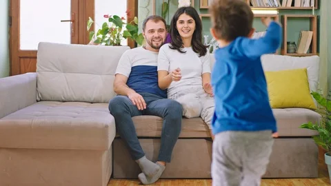 Two kids have a fun time with their young parents while sitting on the sofa the Stock Footage 127917749