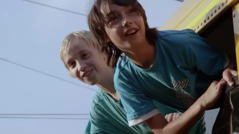 Two kids out bus window on last day of school Stock Footage 337940540