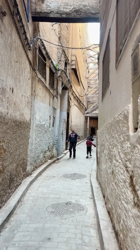 Two kids playing and running towards the camera in a narrow, cobbled street 動画素材 339633794