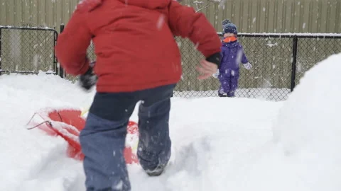 Two Kids Playing In the Backyard on a Snow Day Stock Footage 149460852