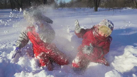 Two kids playing together throwing the snow on winter park Stock Footage