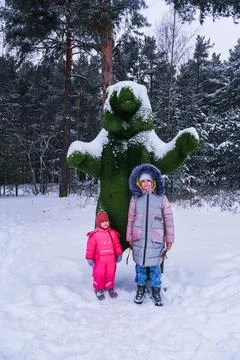 Two kids posing in front of topiary bear in winter forest. Children enjoying Stock Photos