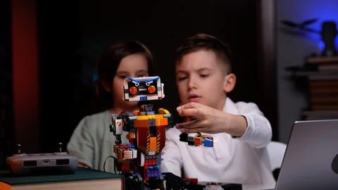 Two kids programming robot from building blocks at home Foto stock