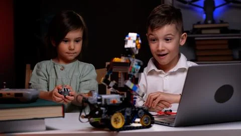Two kids programming robot from laptop using wireless controller Foto stock