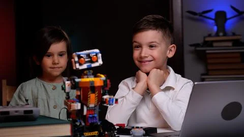 Two kids programming a robot from a laptop at home Foto stock