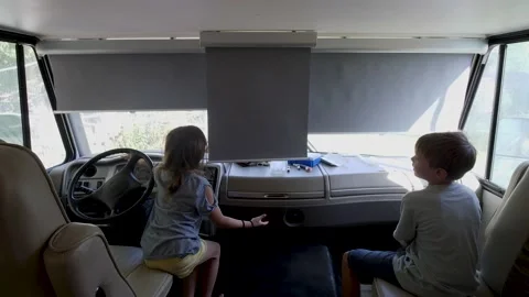Two kids pulling up gray pull down blinds in an RV Stock-Footage 154513982