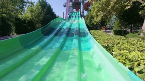 Two kids racing down parallel water slides on blue mats at a water park. Action Stock Footage 316402802