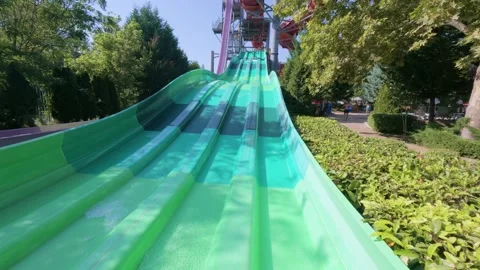 Two kids racing down parallel water slides on blue mats at a water park. Action Stock Footage 316402937