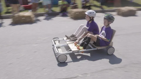 Two kids ride soap box derby car down hill Vidéo 311031845