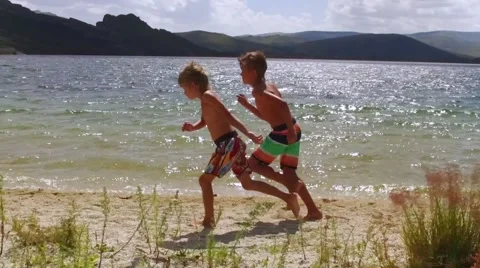 Two kids running on the beach in slow motion Stock Footage 68175701