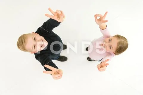 The two kids show two finger on the white background. View from above Stock Photos