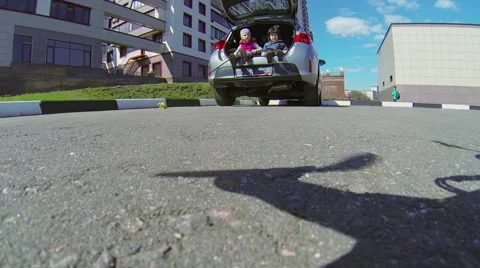 Two kids sit in car boot and watch quadrocopter Stock Footage 42752360