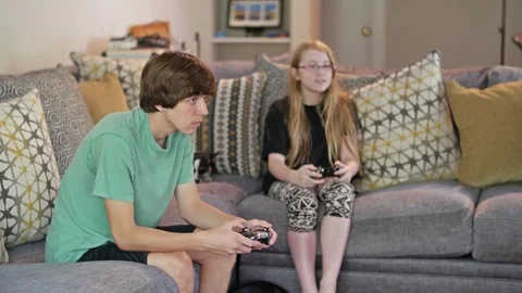 Two kids sitting on a couch playing video games Stock Footage 71896305