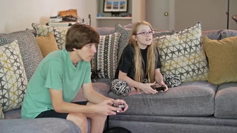 Two kids sitting on a couch playing video games Stock Footage 71896812