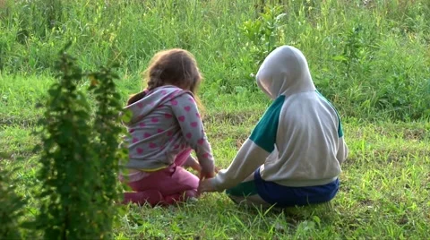 Two kids sitting on green grass and play with bugs and ants, back to camera Stock Footage 63395544