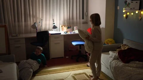 Two kids in their room is having a pillow fight before sleep Stock Footage 297676331