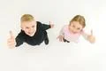 The two kids thumb up on the white background. View from above Photo