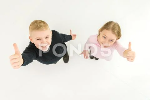 The two kids thumb up on the white background. View from above Stock Photos
