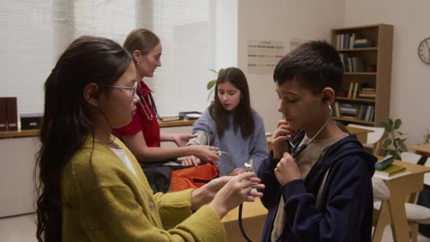 Two Kids Using Stethoscope During Interactive Presentation in School Stock Footage 328327666