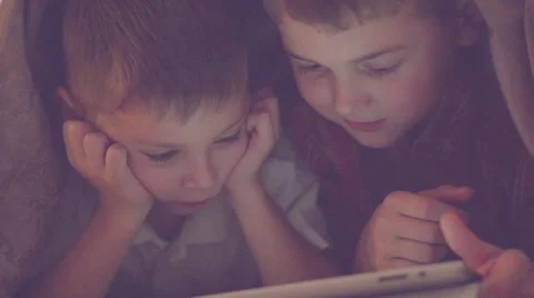 Two kids using tablet pc under blanket at night. Stock Footage 67356477
