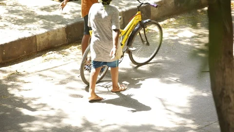 Two-kids-walking-a-bicycle Stock Footage 129742381