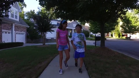 Two kids walking outside a beautiful neighborhood Stock Footage 75496025