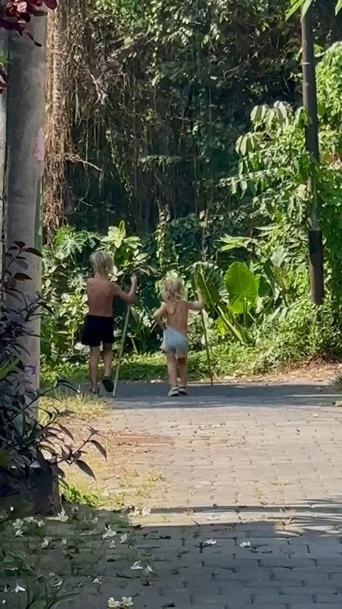 Two kids walking through the jungle with sticks funny Stock Footage 254873447
