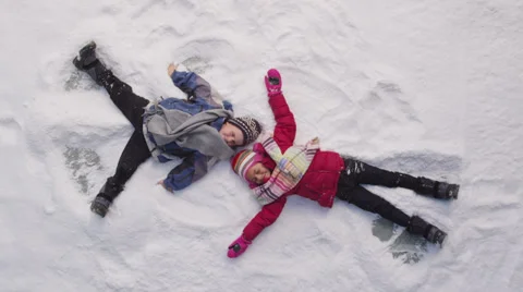 Two kids in winter making snow angels Stock Footage