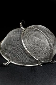 Two kitchen sieves on black background, decoration Stock Photos