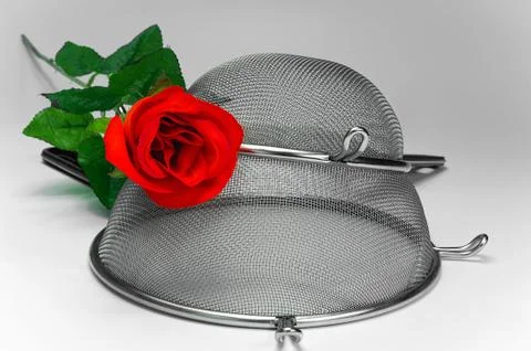 Two kitchen sieves with red rode on white background, decoration Stock Photos