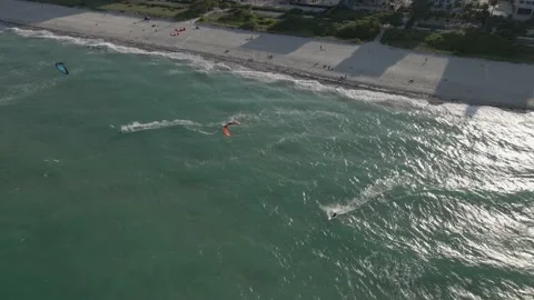 Two kite surfers follow parallel lines out from sandy urban beach Stock Footage 168598492