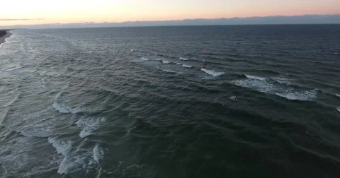 Two kite surfers surfing at a sunset, on a open sea near a peninsula. Stock Footage 68010715
