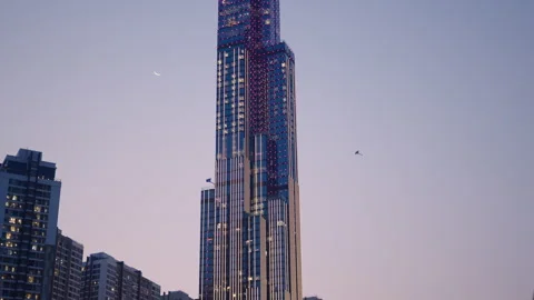 Two kites fly next to landmark 81 skyscraper with colorful lights in ho chi minh Video stock 278695012