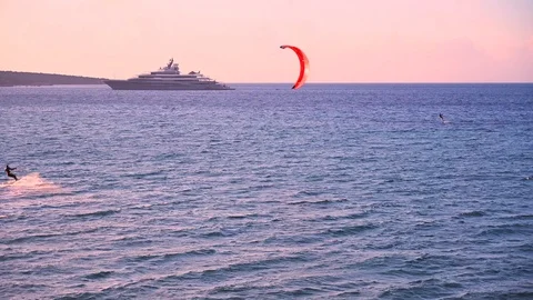 Two kitesurfs and a mega super yacht with helicopter at sunset Stock Footage 107281395