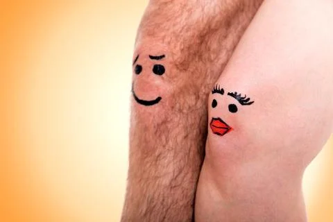 Two knees with faces in front of yellow background Stock Photos